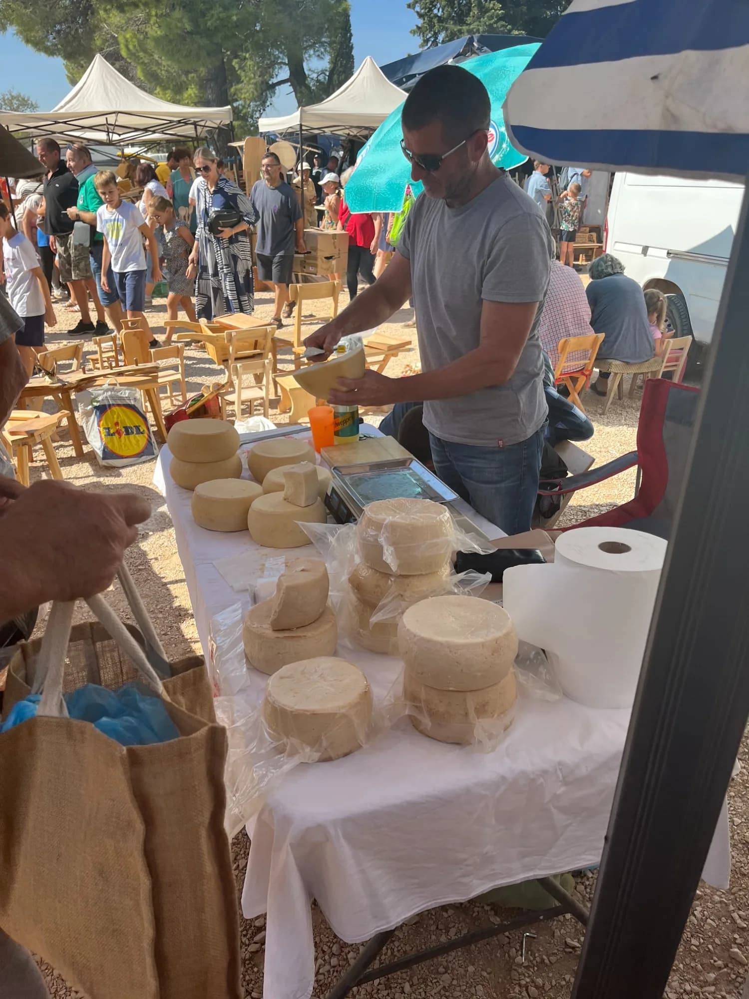 Bauernmarkt Benkovac mit Käselaiben und Verkäufer am Stand