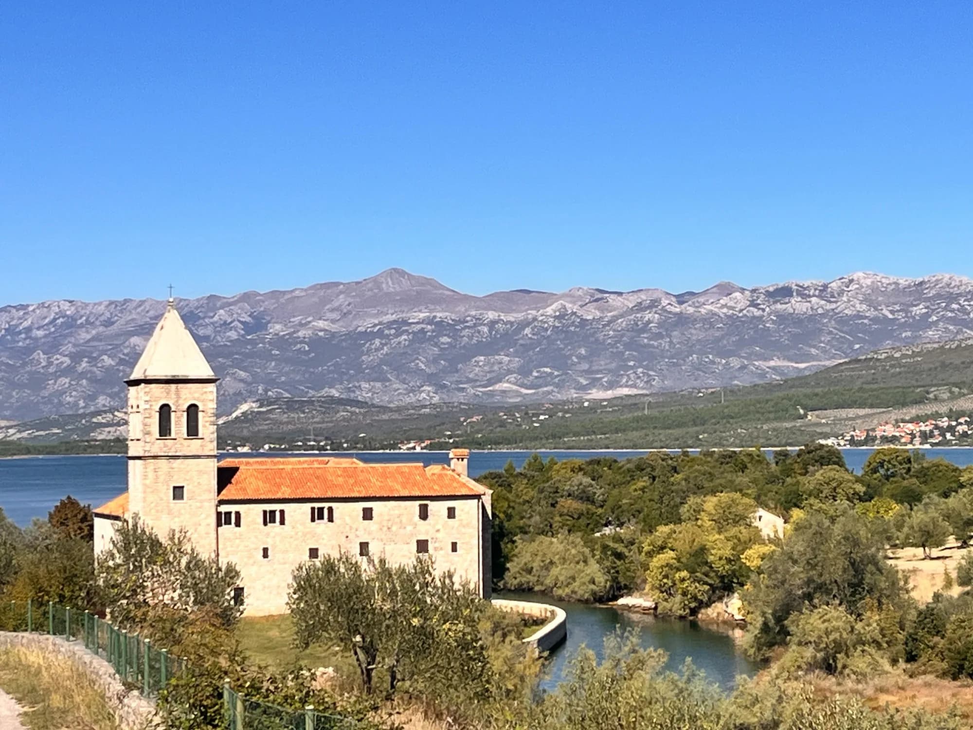 Steinkirche mit Glockenturm an Flussmündung vor dem Velebit-Gebirge